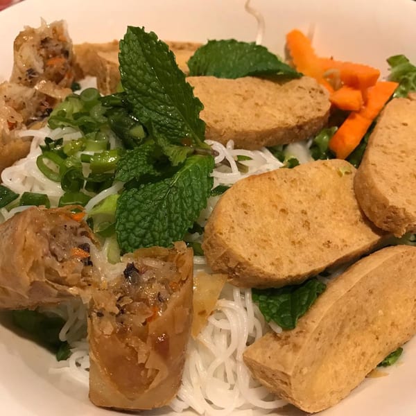 Vietnamese vermicelli bowl with crispy spring rolls, fried tofu, mint, and carrots.